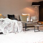 Wohnen mit Kamin Lounge Felldecke Stehleuchte Beleuchtung Wohnen Couch mit Kissen dekorieren Teppich Wohnzimmer gestalten