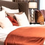 Schlafzimmer rote Decke Kissendekoration auf Bett Tischleuchte Inneneinrichtung Ideen Einrichtungsideen Kundenprojekt Einrichtungskonzept Interior Design Räume planen
