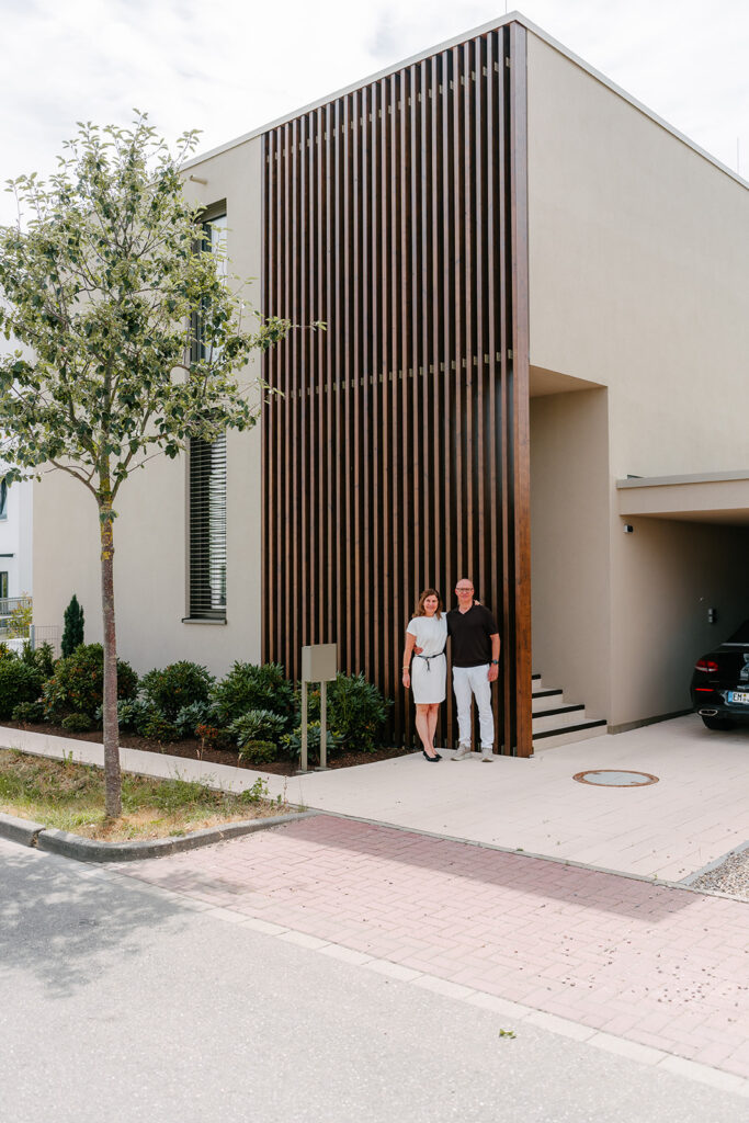 Fassade des fertigen Hauses mit den Bauherren